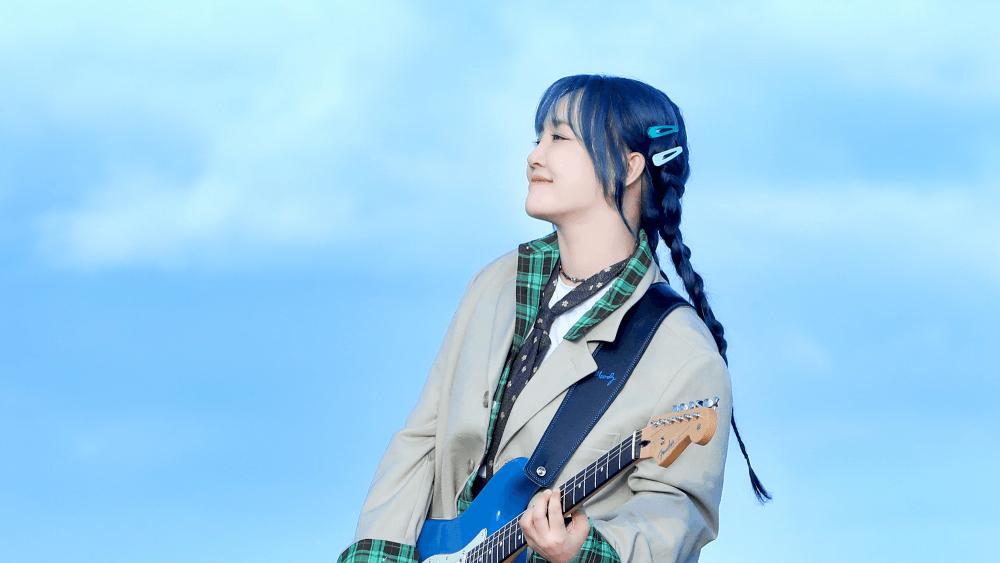 파도치는 바다 배경 위에 윤하가 여행가방을 베고 누워있는 장면