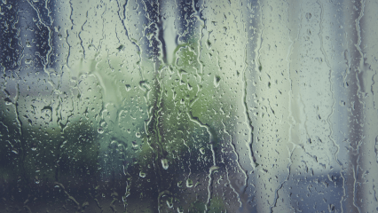 비가 내리는 흐린 날을 배경으로 빗물이 흘러내리는 창문